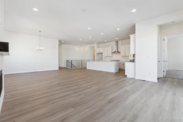 unfurnished living room featuring a chandelier and light wood-type flooring