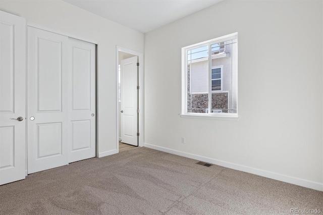 unfurnished bedroom featuring light colored carpet and a closet