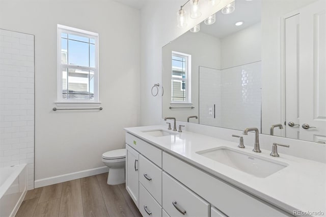 full bathroom with vanity, hardwood / wood-style floors, washtub / shower combination, and toilet