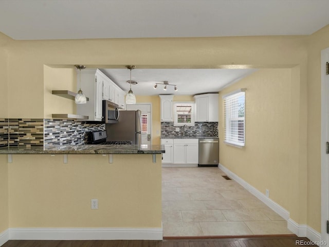 3971 W Kentucky Ave, Denver, CO 80219 - kitchen featuring stainless steel appliances, a peninsula, decorative backsplash, dark stone countertops, and white cabinets