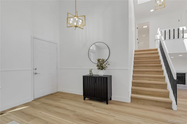 entrance foyer featuring a chandelier, light wood finished floors, stairs, and recessed lighting