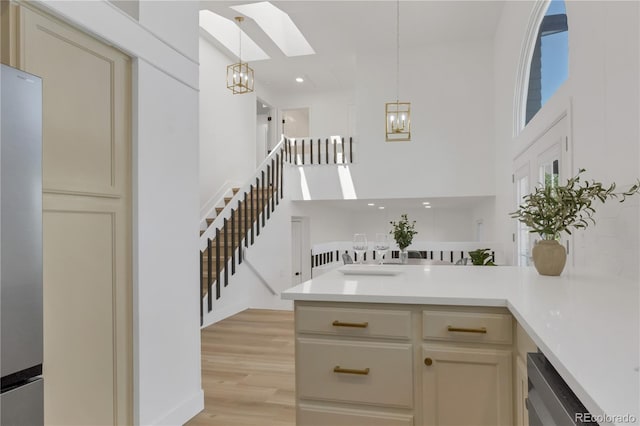 bar area featuring a skylight, a chandelier, appliances with stainless steel finishes, hanging light fixtures, and a high ceiling
