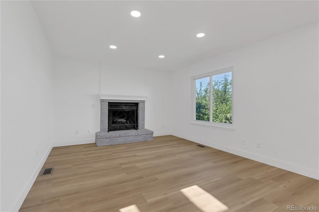 unfurnished living room featuring baseboards, a fireplace, light wood-type flooring, and recessed lighting