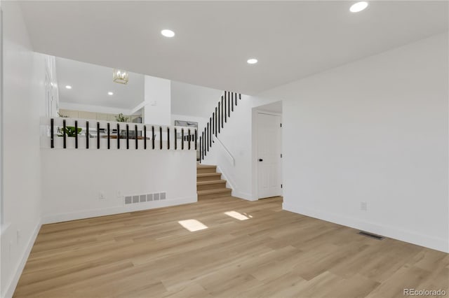 unfurnished living room featuring stairs, light wood finished floors, recessed lighting, and baseboards
