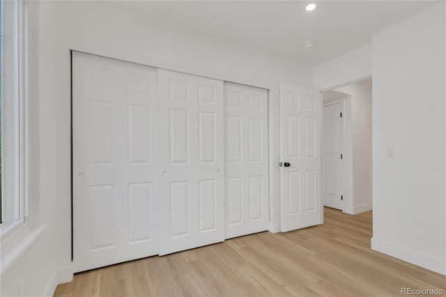 unfurnished bedroom featuring light wood-style flooring, baseboards, a closet, and recessed lighting