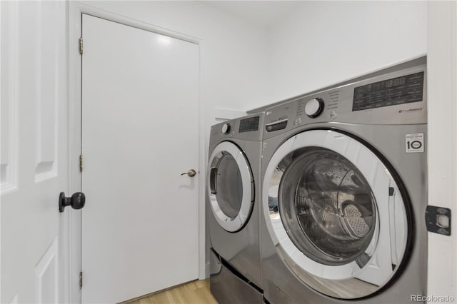 laundry room with independent washer and dryer and light wood finished floors