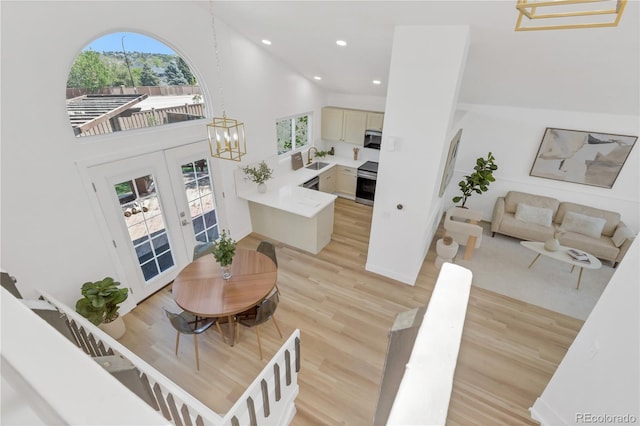 dining area featuring high vaulted ceiling, light wood-style floors, french doors, recessed lighting, and a chandelier