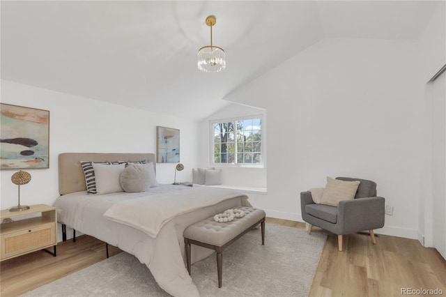 bedroom featuring wood finished floors, lofted ceiling, a chandelier, and baseboards