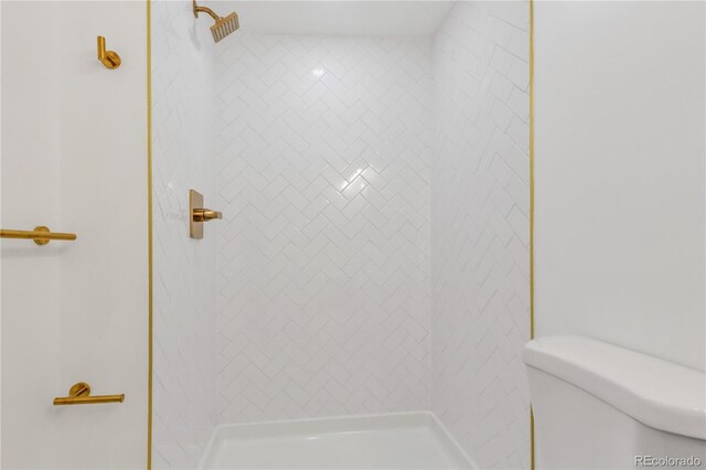 full bathroom featuring a tile shower and toilet