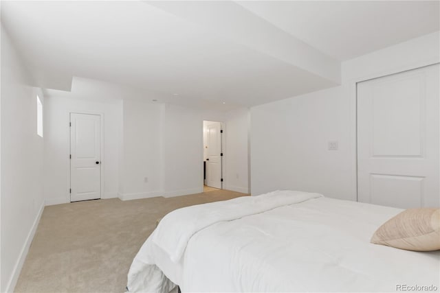 bedroom with light colored carpet, baseboards, and a closet