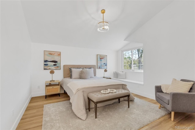 bedroom with light wood finished floors, vaulted ceiling, a chandelier, and baseboards