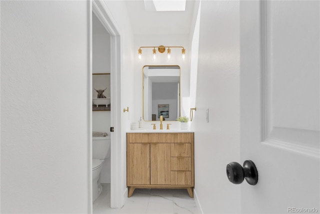 bathroom with baseboards, toilet, vanity, and marble finish floors