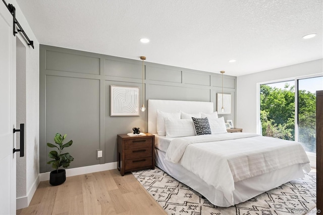 3206 S Pontiac St, Denver, CO 80224 - bedroom featuring a barn door, light wood finished floors, recessed lighting, and a textured ceiling