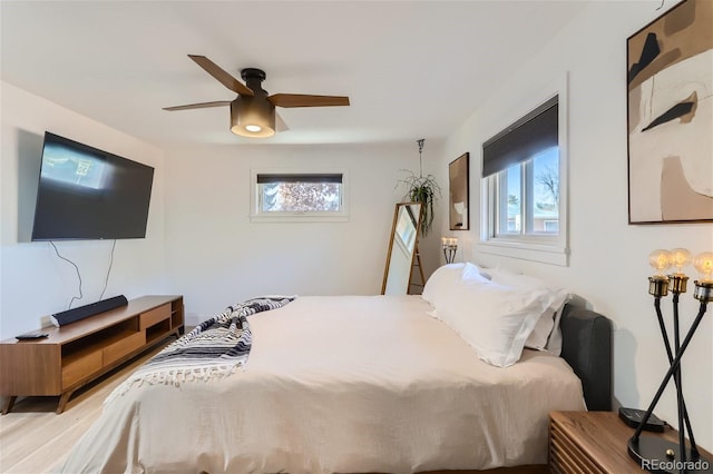 bedroom with ceiling fan, light hardwood / wood-style floors, and multiple windows