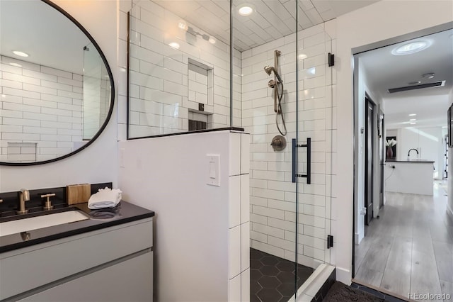 bathroom with wood-type flooring, vanity, and an enclosed shower