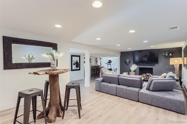 living room featuring light hardwood / wood-style floors and a brick fireplace