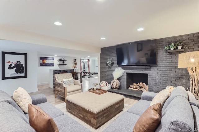 living room featuring light hardwood / wood-style floors, a brick fireplace, and brick wall