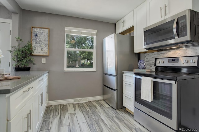 kitchen featuring light hardwood / wood-style floors, white cabinets, tasteful backsplash, and appliances with stainless steel finishes