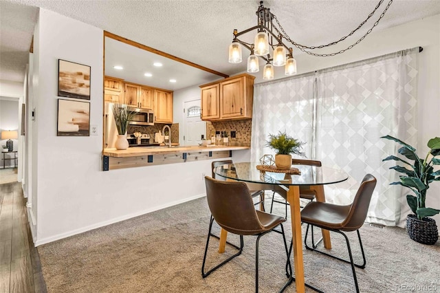 dining room with sink, hardwood / wood-style flooring, a chandelier, and a textured ceiling