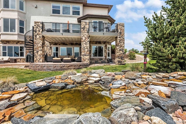 7724 Kryptonite Ln, Castle Rock, CO 80108 - rear view of house featuring an outdoor hangout area, a balcony, a garden pond, stucco siding, and a patio area
