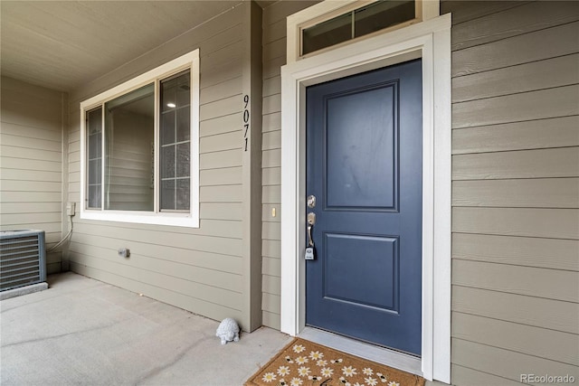 view of exterior entry with central AC and covered porch