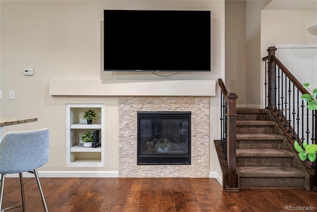 living room with built in shelves, wood finished floors, baseboards, and stairs