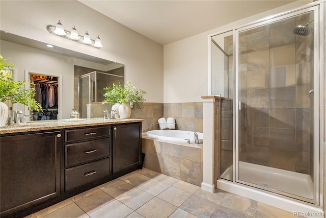 bathroom featuring a stall shower, a bath, vanity, a spacious closet, and tile patterned flooring