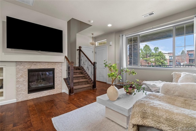 living room featuring wood finished floors, stairs, recessed lighting, a stone fireplace, and baseboards