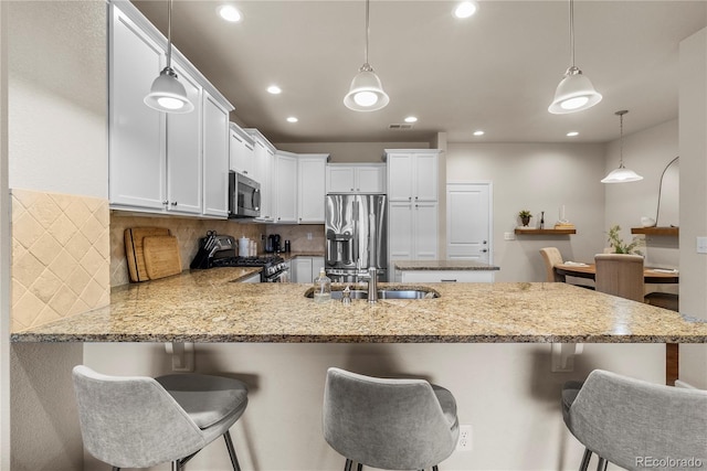 kitchen with stainless steel appliances, a peninsula, backsplash, white cabinetry, and recessed lighting