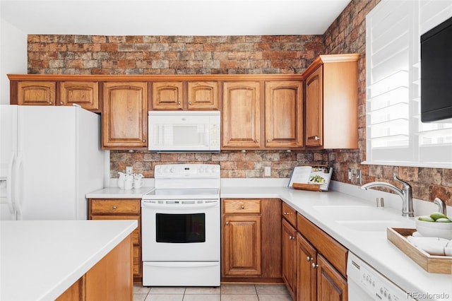 kitchen with brown cabinetry, light countertops, white appliances, and a sink