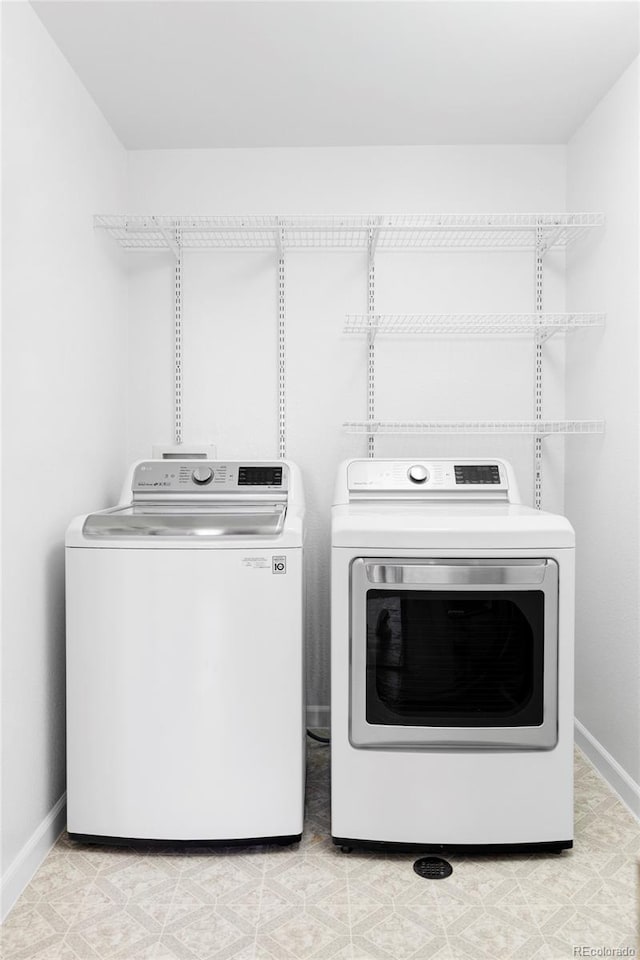 clothes washing area featuring washing machine and clothes dryer, baseboards, and laundry area