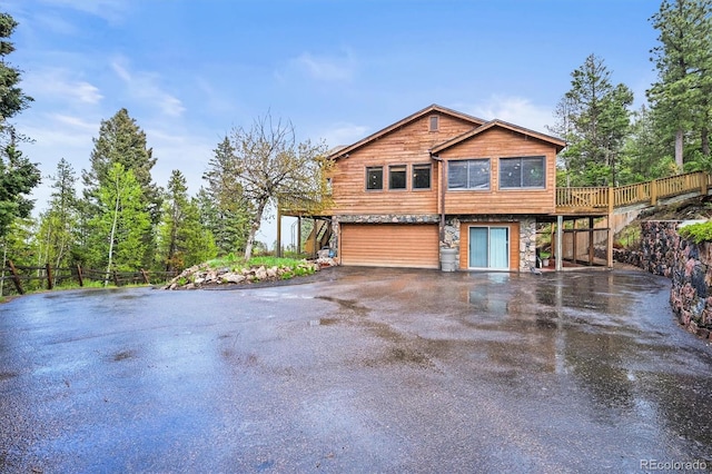 29825 Kennedy Gulch Rd, Conifer, CO 80433 - view of home's exterior featuring driveway, an attached garage, stone siding, and a wooden deck