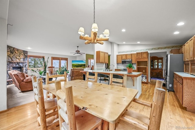 29825 Kennedy Gulch Rd, Conifer, CO 80433 - dining room featuring light wood finished floors, a chandelier, recessed lighting, ceiling fan, and a fireplace