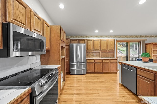 29825 Kennedy Gulch Rd, Conifer, CO 80433 - kitchen with appliances with stainless steel finishes, light wood-style flooring, recessed lighting, and brown cabinetry
