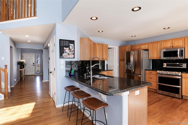 kitchen featuring a sink, decorative backsplash, appliances with stainless steel finishes, and light wood finished floors