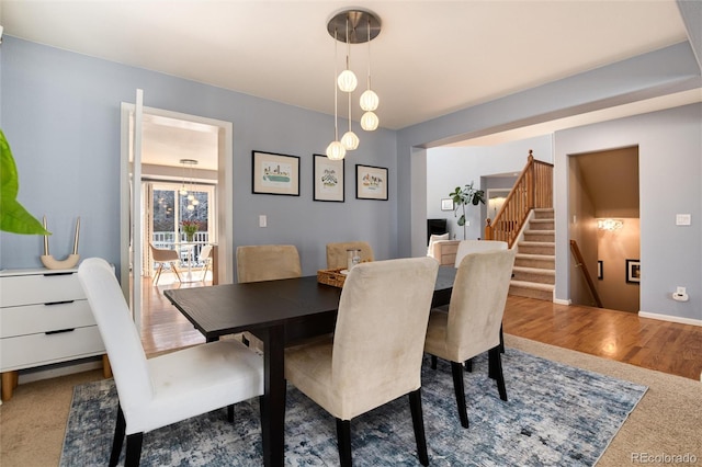 dining space with stairway, a notable chandelier, and wood finished floors