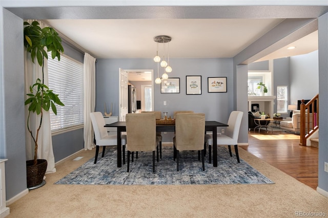 dining room featuring baseboards, stairway, carpet floors, an inviting chandelier, and wood finished floors