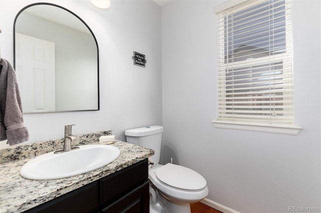 bathroom with vanity, toilet, wood finished floors, and baseboards