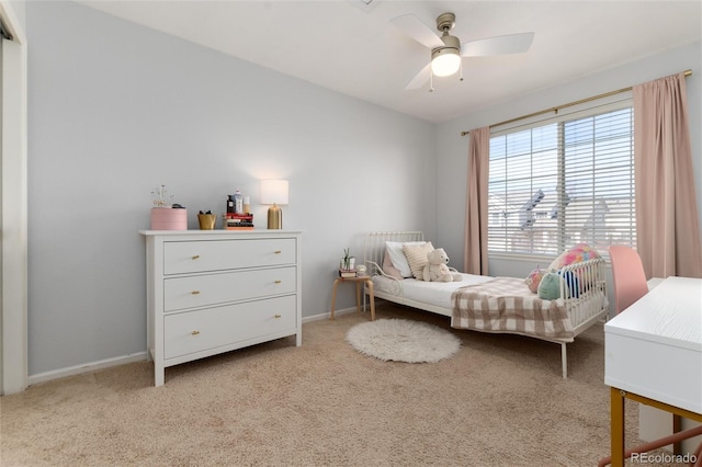 bedroom featuring light colored carpet, a ceiling fan, and baseboards