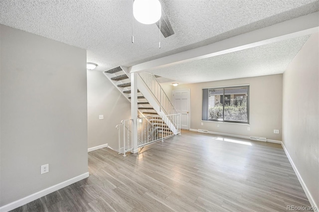 interior space with stairs, wood finished floors, visible vents, and baseboards