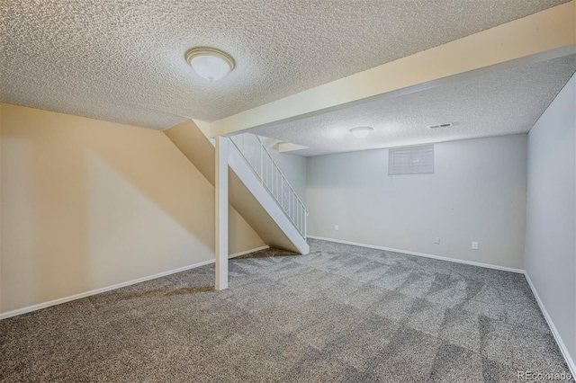 finished basement featuring a textured ceiling, stairs, baseboards, and carpet floors