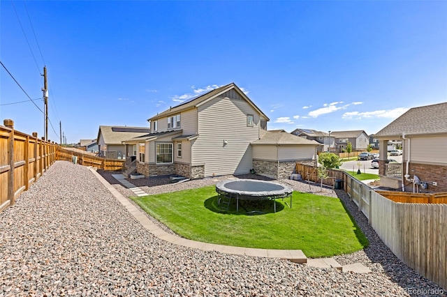 1061 S De Gaulle Ct, Aurora, CO 80018 - back of property with a trampoline, stone siding, a residential view, and a fenced backyard