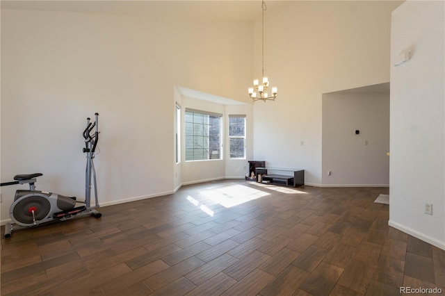 interior space featuring baseboards, a high ceiling, a chandelier, and dark wood-style flooring