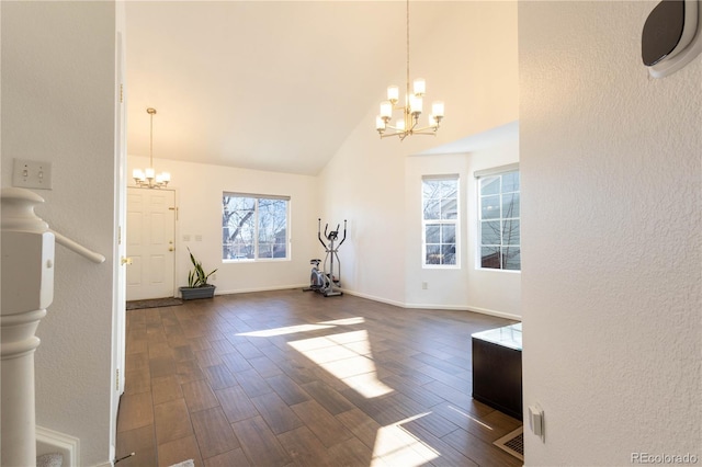 interior space featuring a chandelier, high vaulted ceiling, dark wood-type flooring, and baseboards