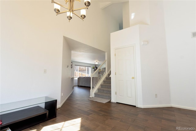 foyer featuring visible vents, baseboards, a towering ceiling, wood finished floors, and stairs