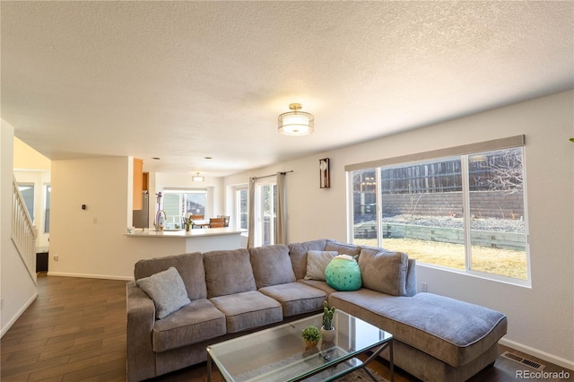 living area featuring a textured ceiling, dark wood finished floors, visible vents, and baseboards