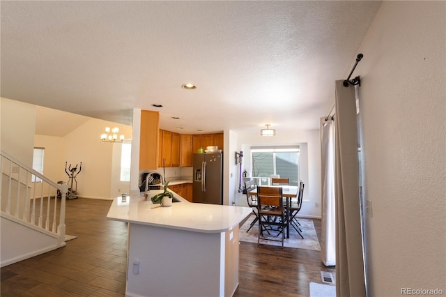 kitchen featuring light countertops, stainless steel fridge, dark wood finished floors, and a peninsula