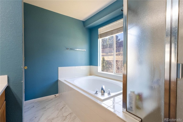 bathroom featuring marble finish floor, baseboards, a garden tub, and vanity