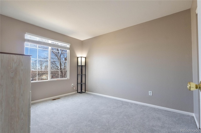 carpeted spare room featuring visible vents and baseboards