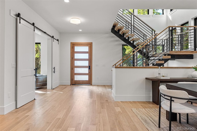 foyer entrance with light hardwood / wood-style floors and a barn door